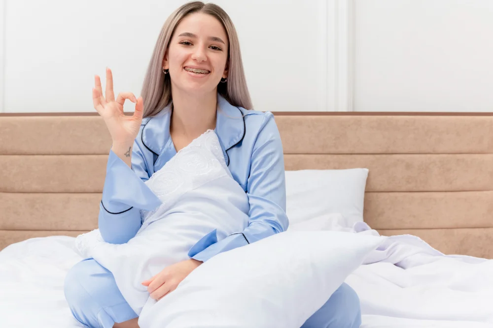 Young Beautiful Woman Blue Pajamas Sitting Bed Smiling Cherrfully Showing Ok Sign Bedroom Interior